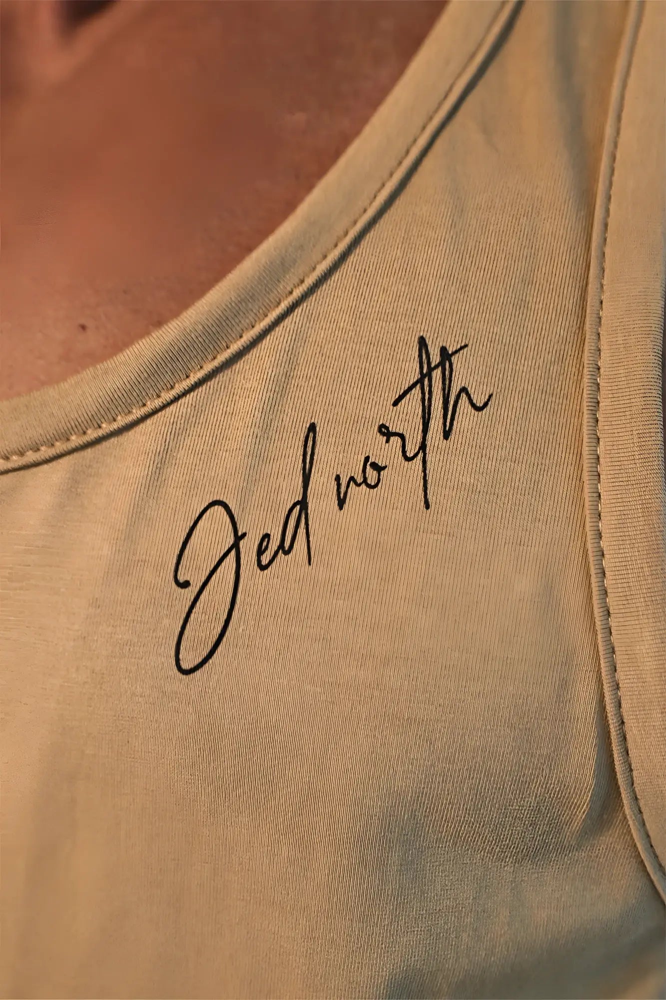 Beige cotton training stringer tank top with black cursive jed north embroidery on the shoulder
