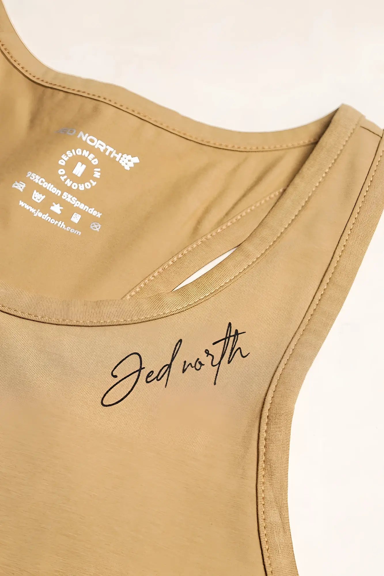 Tan cotton training stringer tank top with sleeveless design and black cursive jed north logo embroidered on front