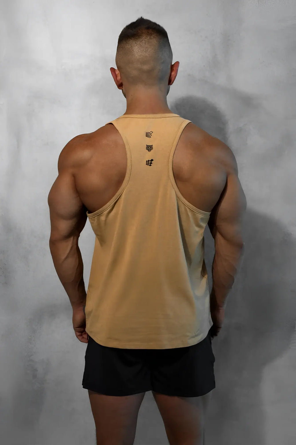 Tan cotton training stringer tank top back view with subtle gradient and three black embroidered logos down center