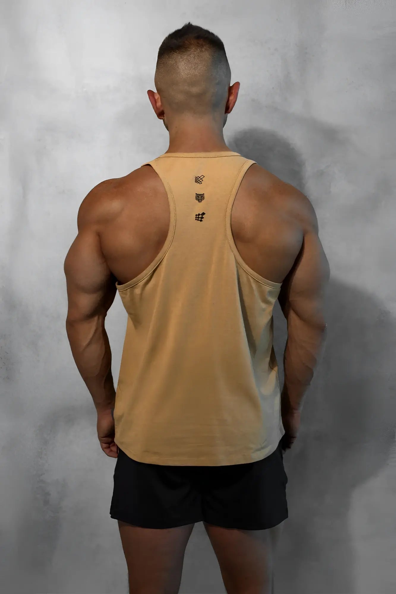 Tan cotton training stringer tank top back view with subtle gradient and three black embroidered logos down center