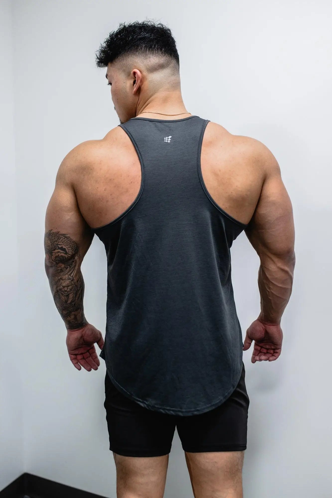 Dark gray sleeveless athletic tank top with subtle logo on upper back for bodybuilding by jed north seen from back