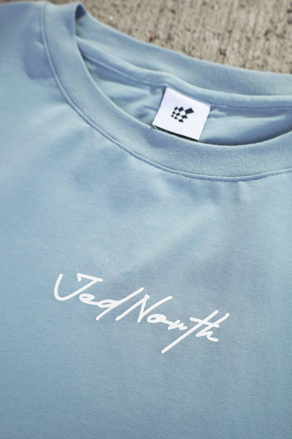 A soft light blue Jed North Energy oversized long sleeve t shirt 2.0 with white cursive logo embroidered front