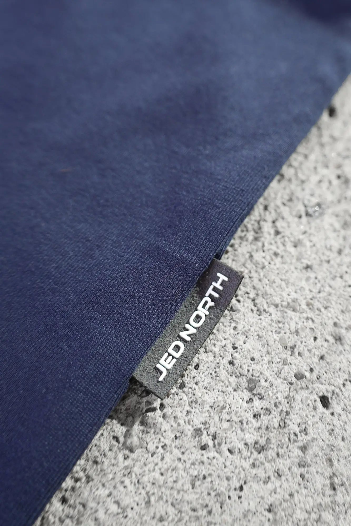 Dark blue fabric with a black woven label showing white jed north text on the jed north energy oversized long sleeve t shirt 2.0