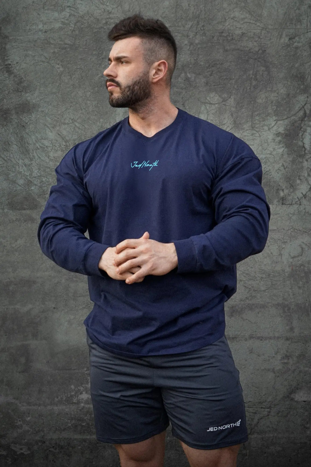 Navy blue jed north energy oversized long sleeve v neck athletic shirt with light teal cursive logo on chest