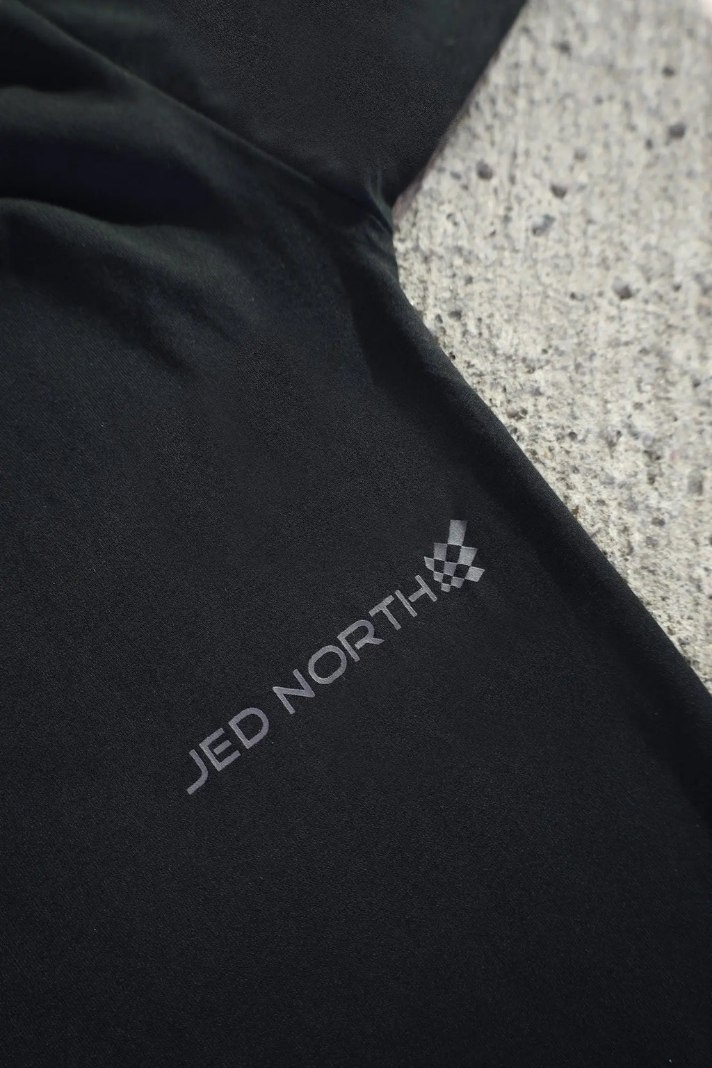 Black fabric of jed north energy oversized long sleeve t-shirt 2.0 obsidian black with gray logo and checkered flag emblem near sleeve