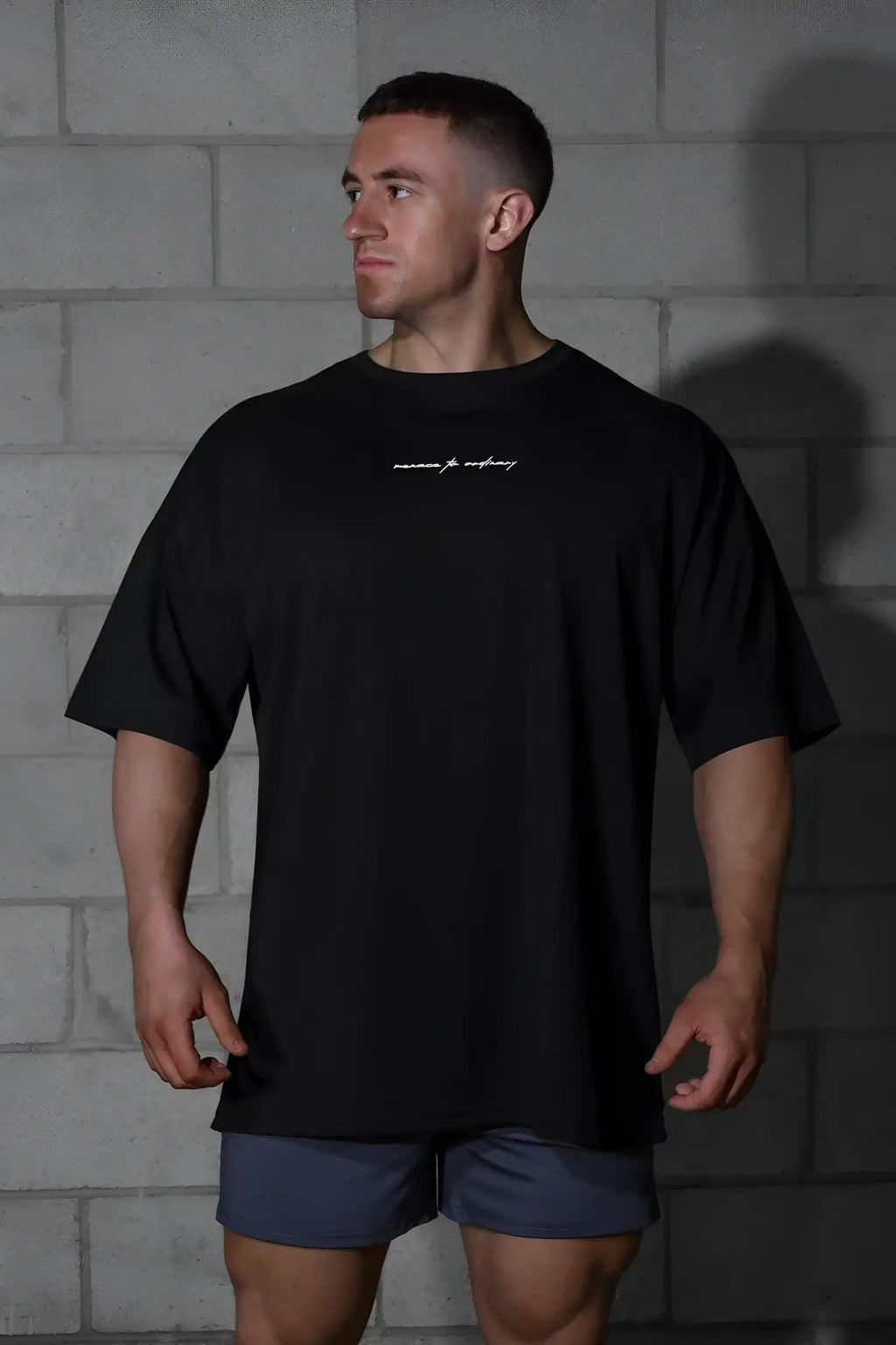Black oversized jed north energy t-shirt with subtle white cursive logo across the chest in menace black color