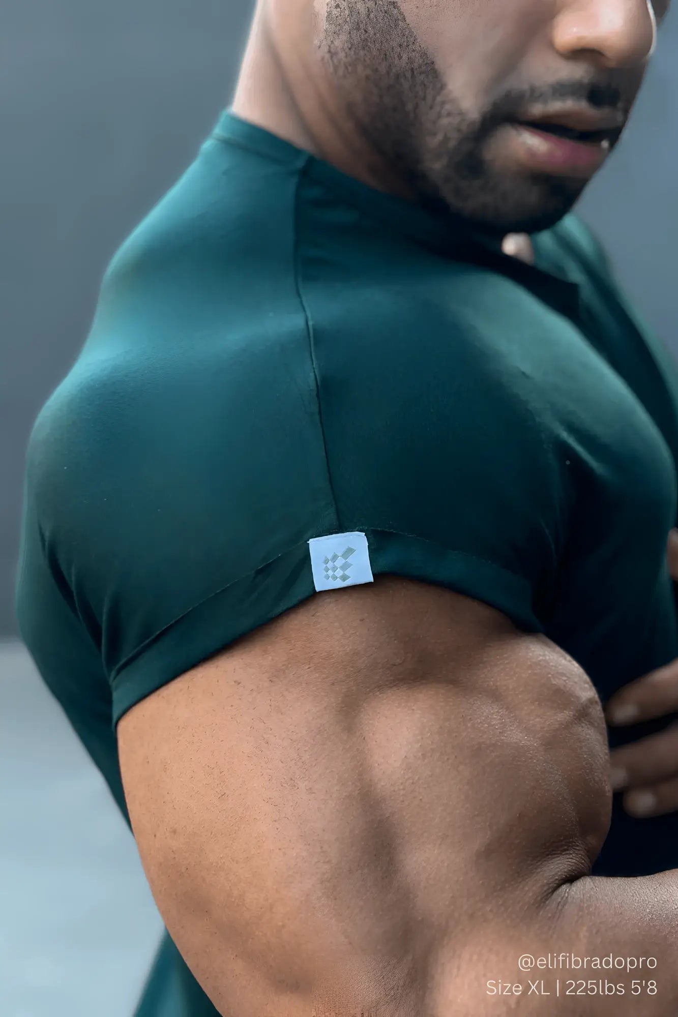 Dark green form-fitting jed north evolve men’s cap sleeve athletic t-shirt with a small white shoulder label