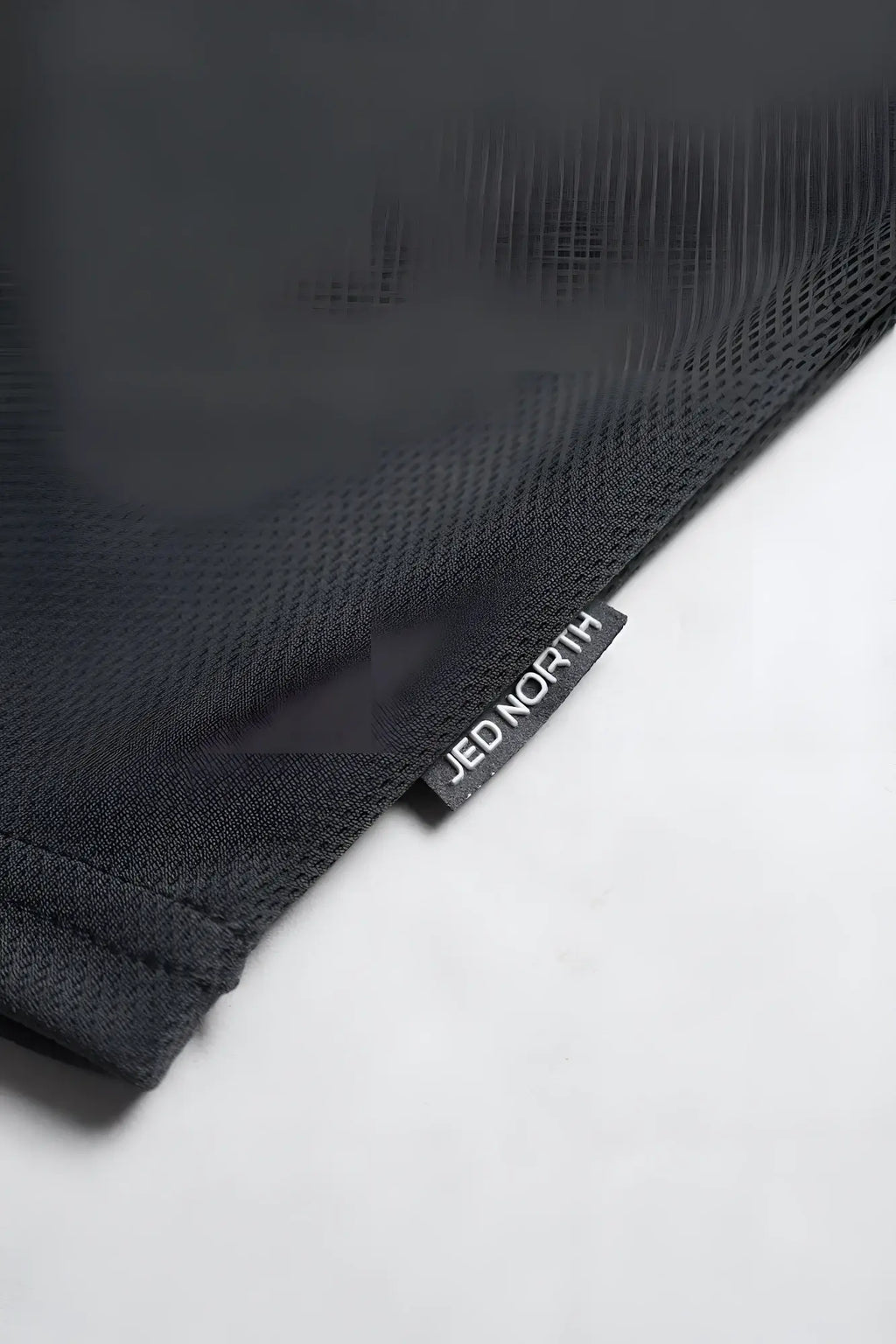 Black textured fast-dry bodybuilding workout stringer with small black tag bearing white jed north text