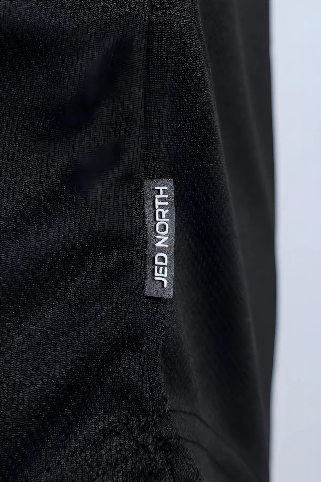 Black textured fast-dry bodybuilding workout stringer with jed north brand tag stitched on the seam