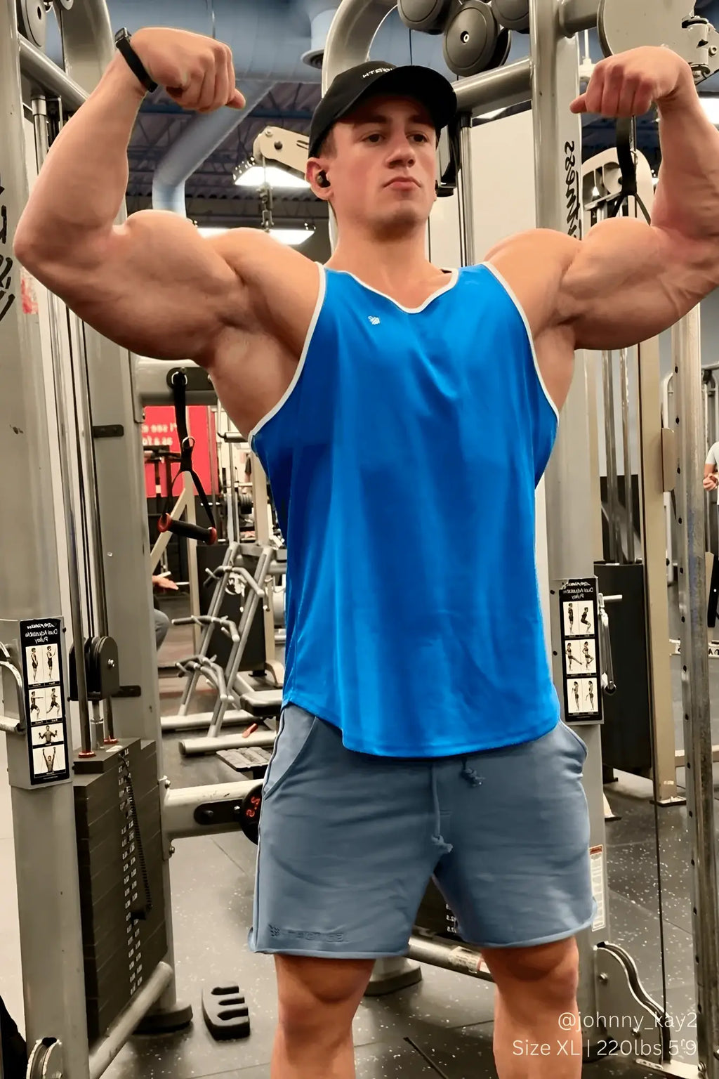 A man wearing a jed north fast-dry bodybuilding workout stringer in blue with white trim and light gray shorts