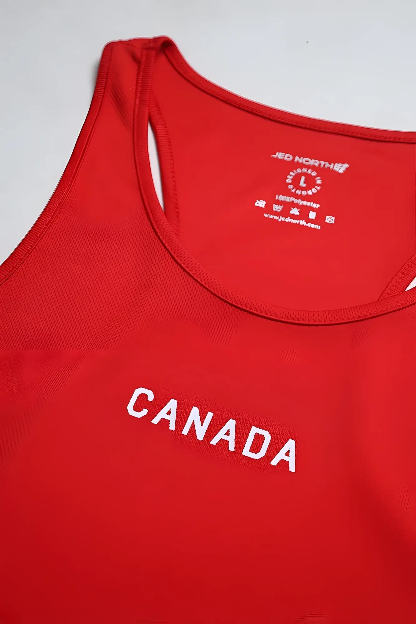 Red fast-dry bodybuilding workout stringer tank top with white canada lettering and brand tag at neckline