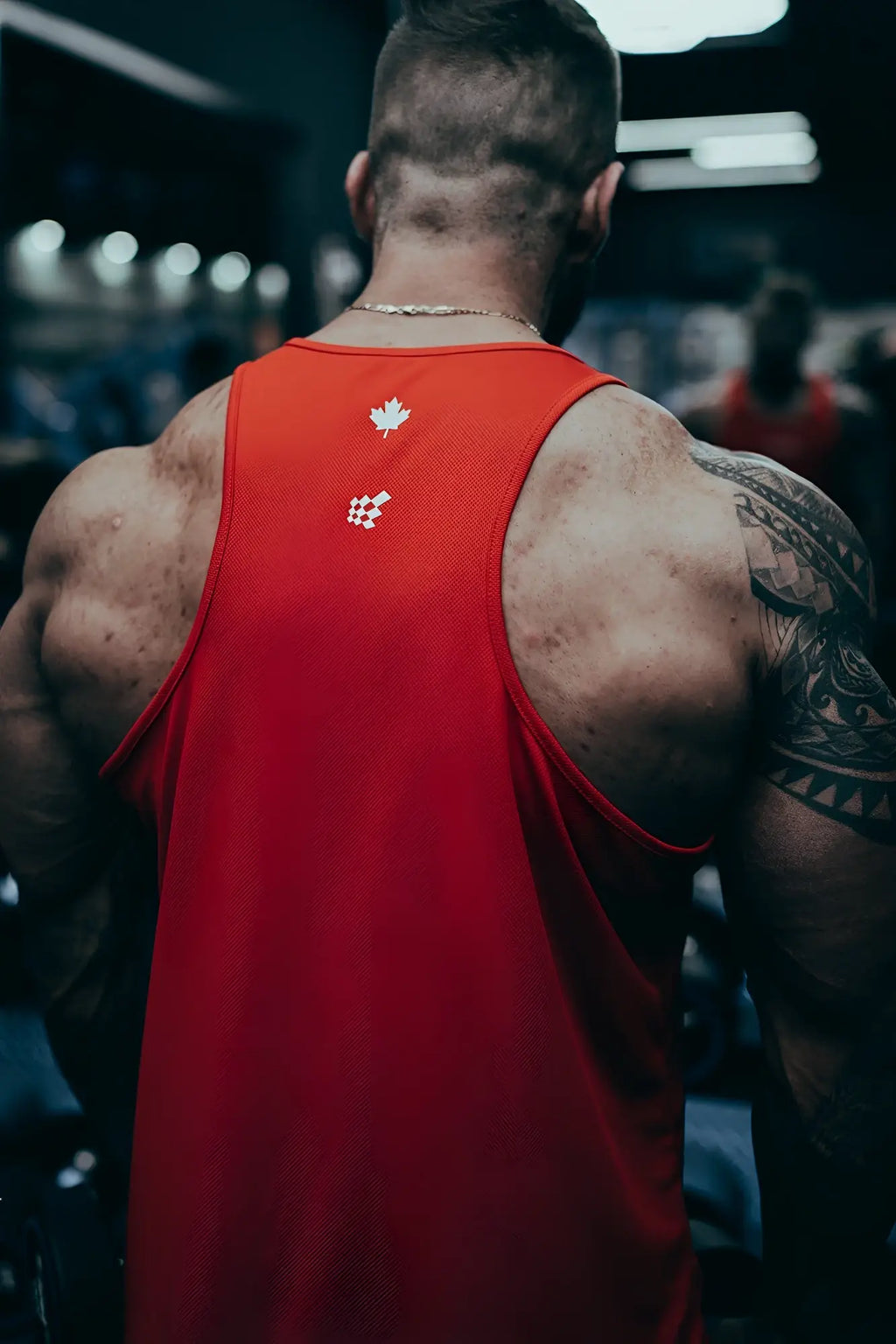 Back view of red fast-dry bodybuilding stringer with white maple leaf and logo emblem for workout use