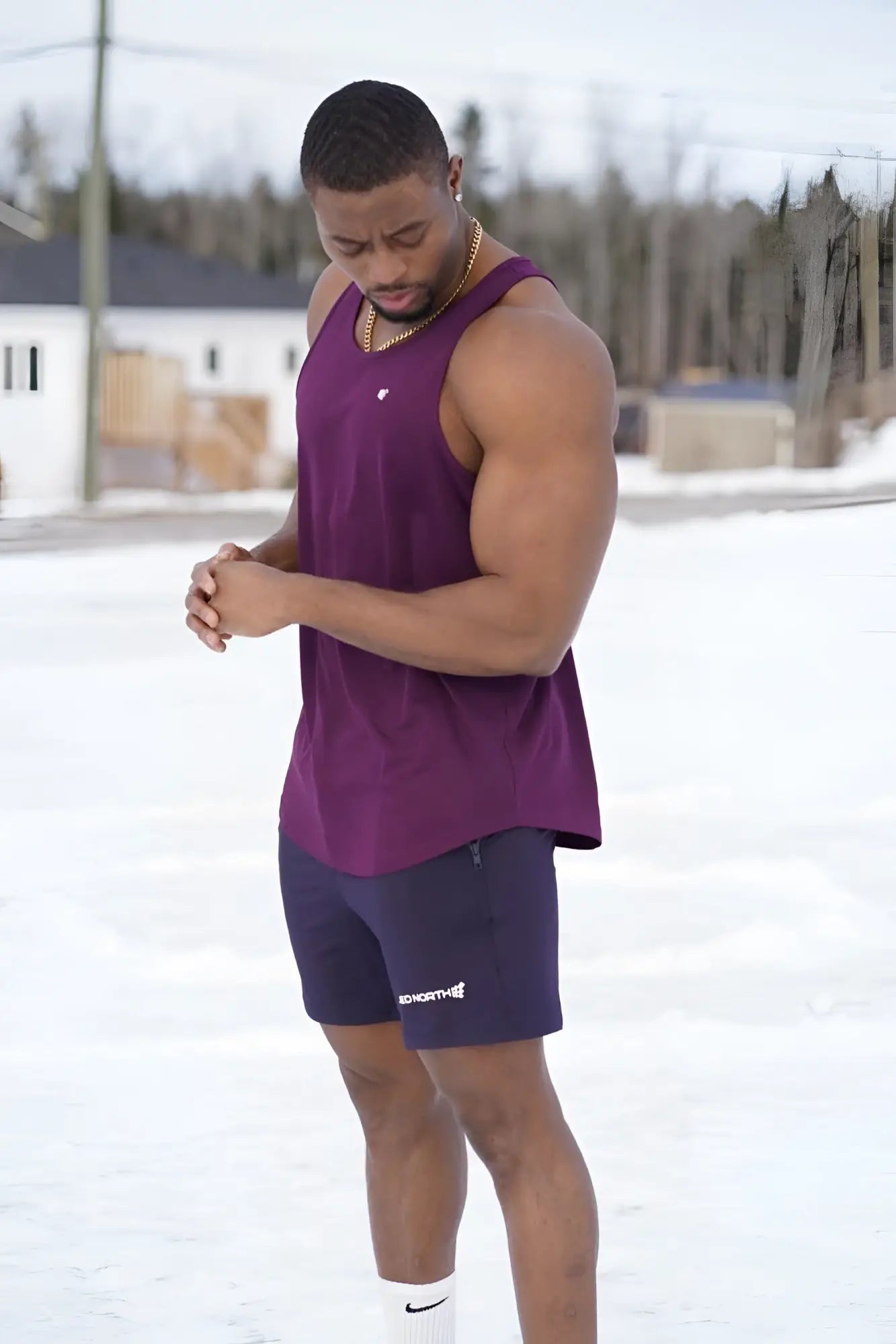A man wearing a dark purple jed north fast-dry sleeveless bodybuilding workout stringer with a white chest logo