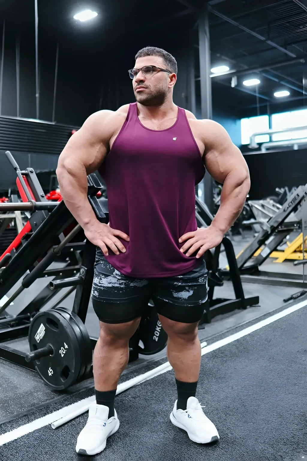 A maroon jed north fast-dry bodybuilding workout stringer tank top worn by a muscular man in a gym setting