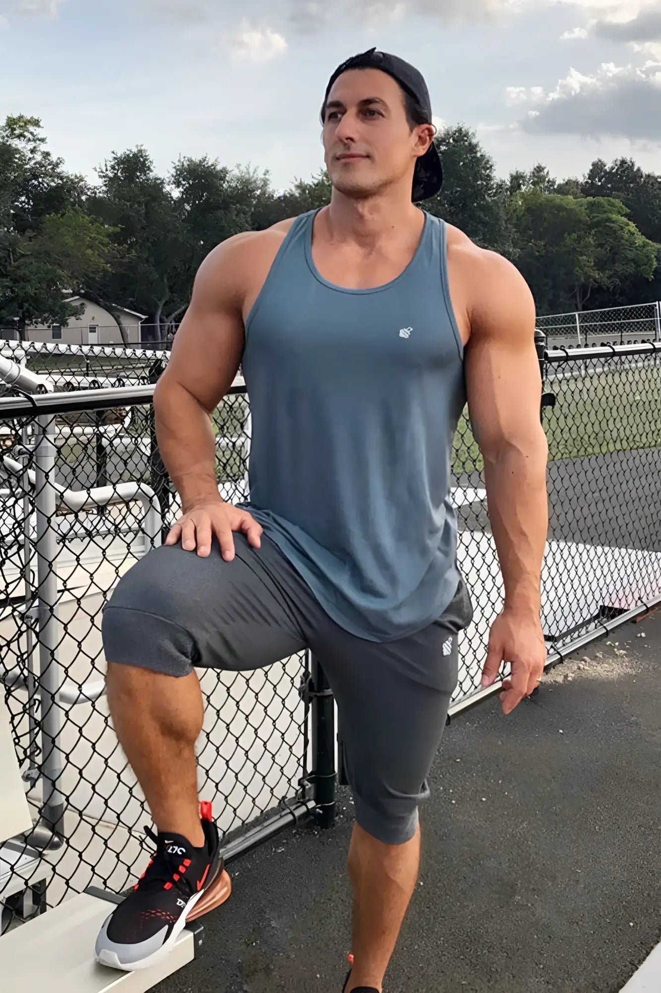 A muscular man wearing a gray jed north fast-dry bodybuilding workout stringer with matching shorts and black red shoes