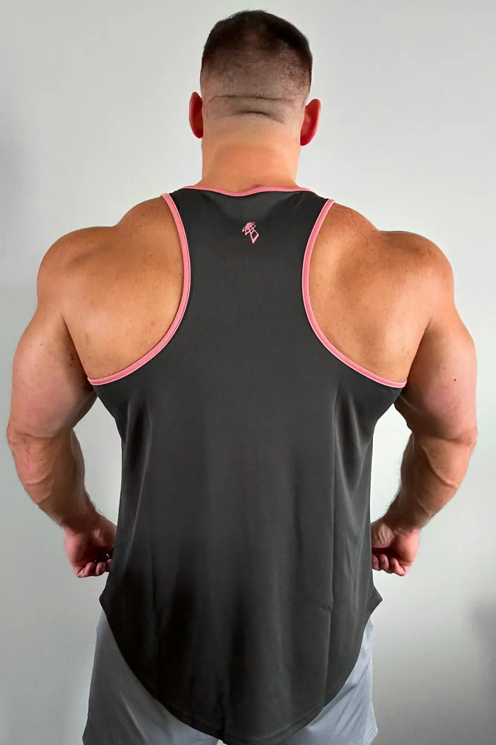Back view of a black fast-dry bodybuilding workout stringer with pink trim and small logo on upper back