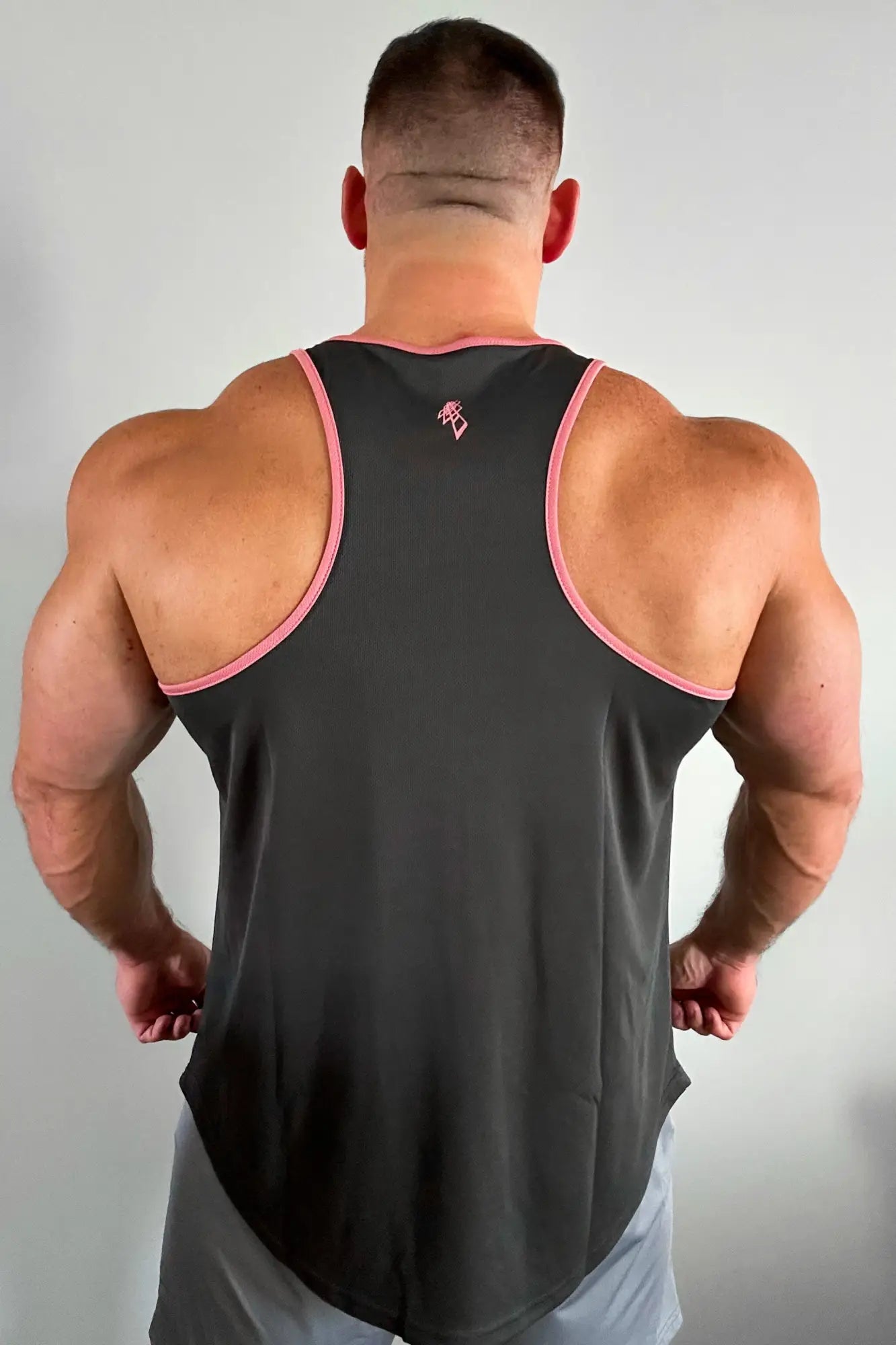 Back view of a black fast-dry bodybuilding workout stringer with pink trim and small logo on upper back