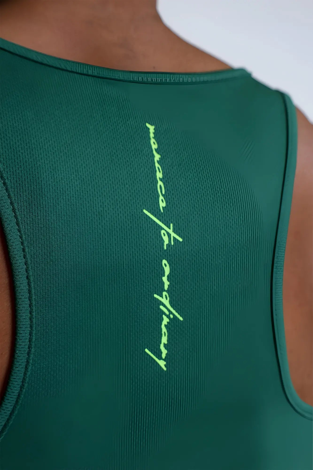 Back view of emerald green sleeveless fast dry bodybuilding workout stringer with neon yellow mosaic of ordinary text
