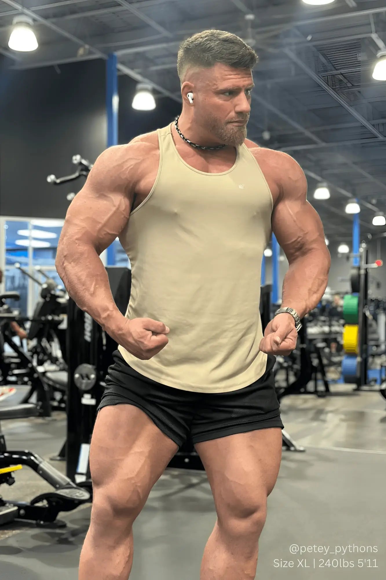 Muscular man wearing a khaki jed north fast-dry bodybuilding workout stringer tank top in a gym setting