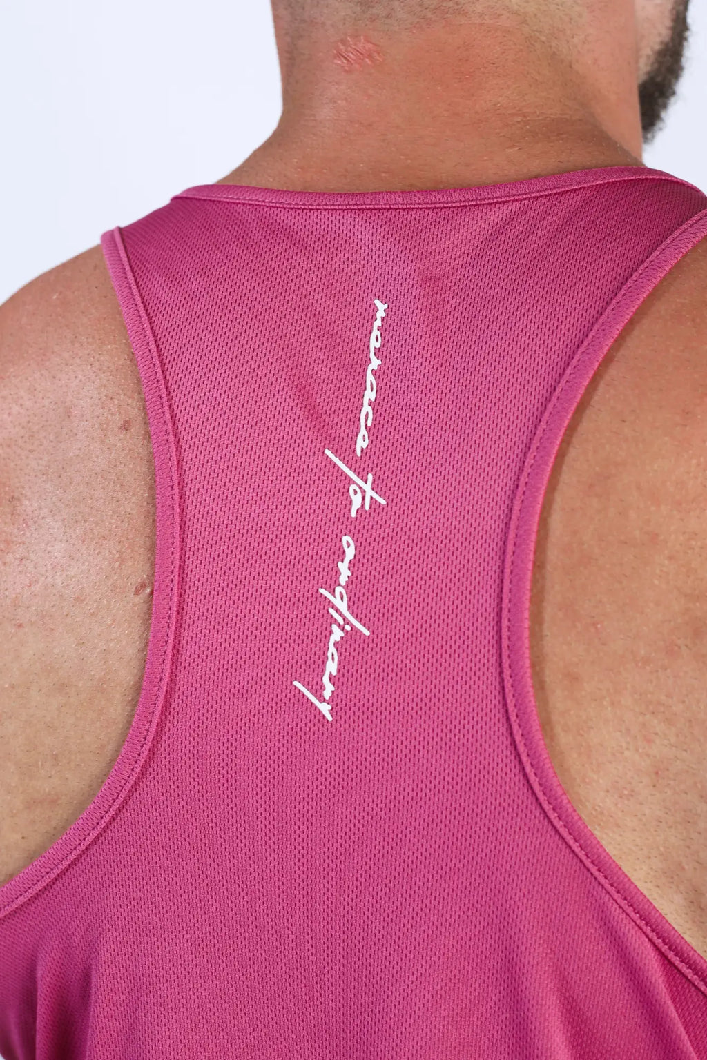 Back view of a vibrant magenta fast-dry bodybuilding workout stringer tank top with mesh texture and white cursive lettering