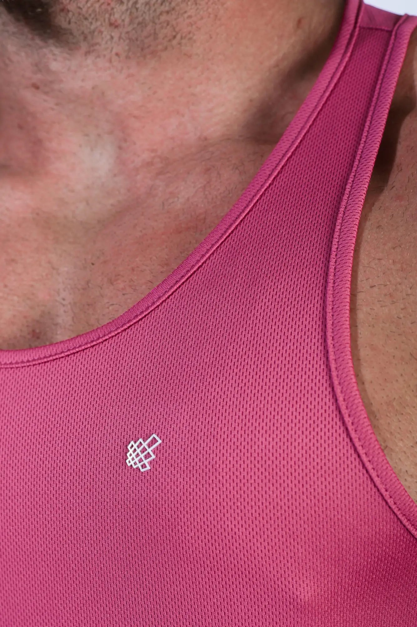 A vibrant magenta fast-dry bodybuilding workout stringer tank top with subtle mesh texture and a white geometric logo