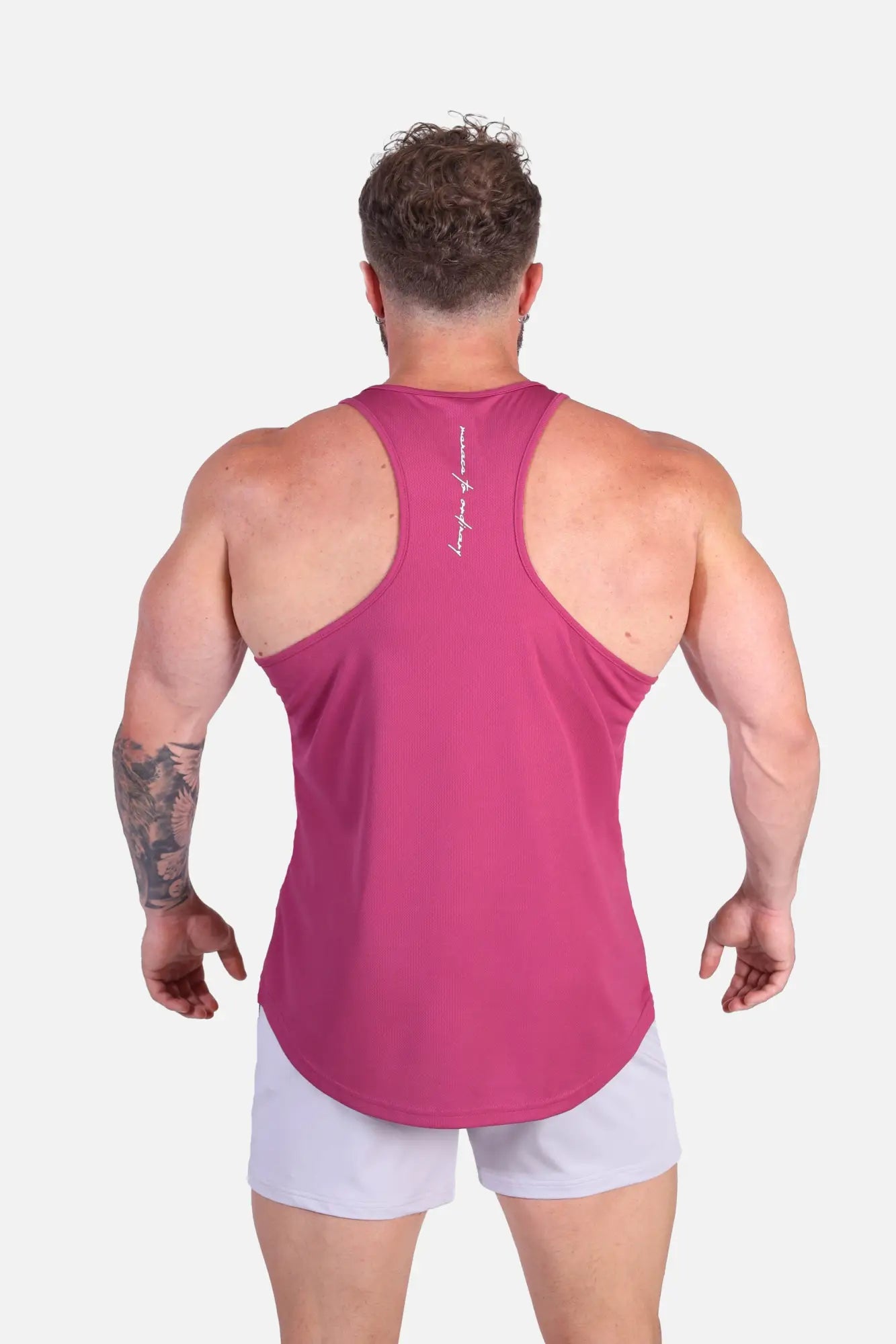 Back view of a vibrant magenta fast dry bodybuilding workout stringer tank top with racerback and white script branding