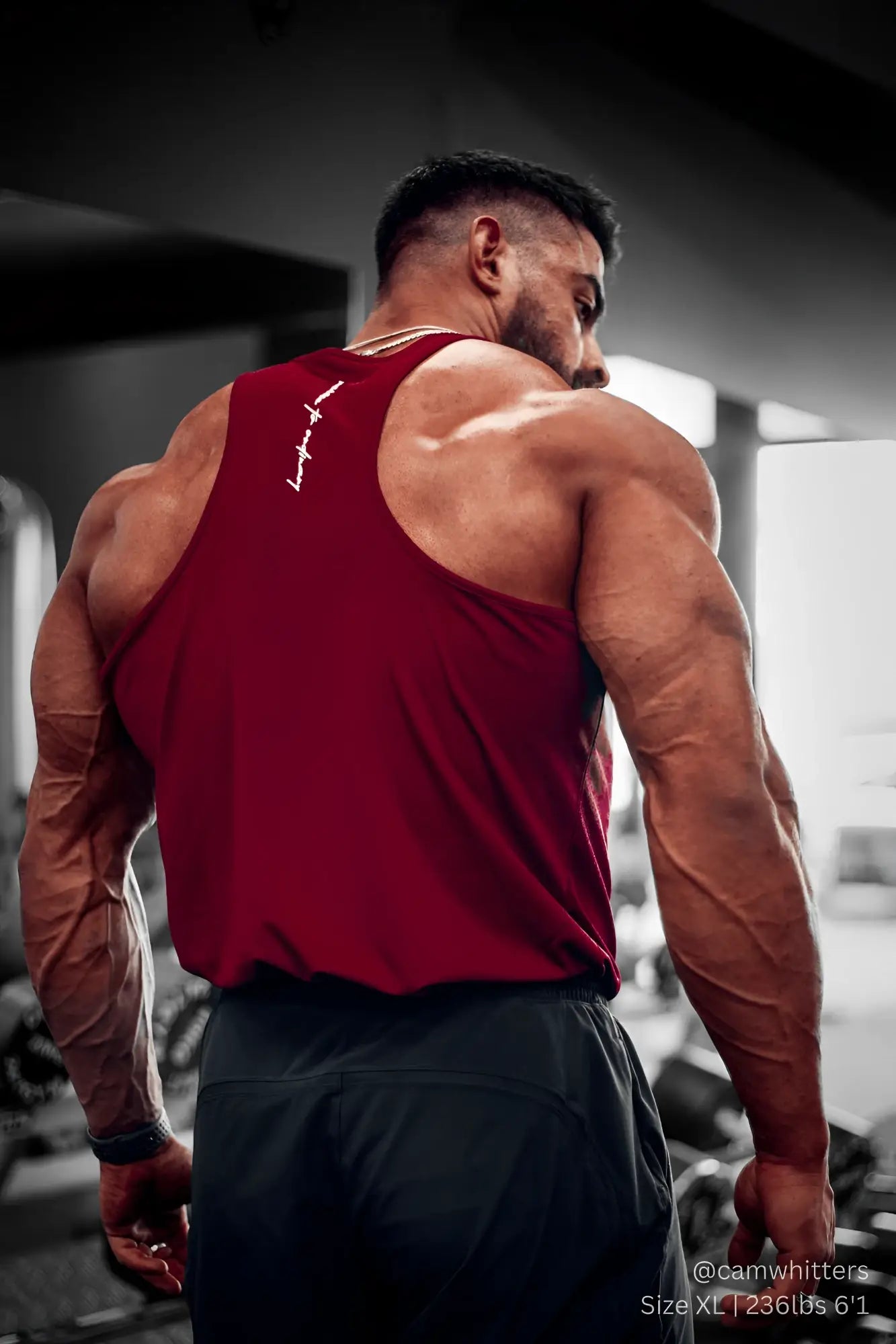 Back view of jed north fast-dry maroon bodybuilding workout stringer tank top with white logo worn by muscular person