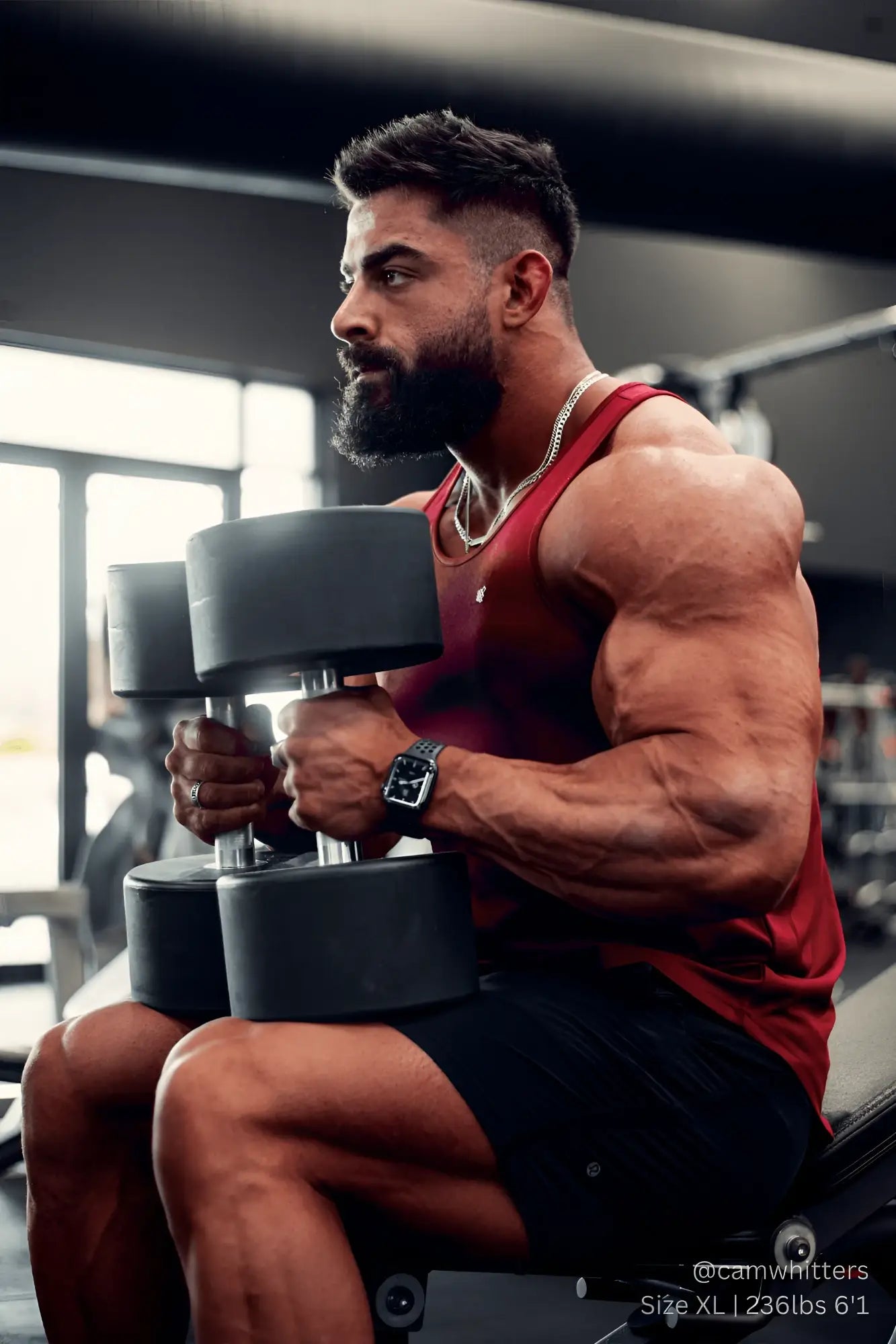 Black dumbbell with matte finish and silver handle shown with jed north fast-dry bodybuilding workout stringer maroon