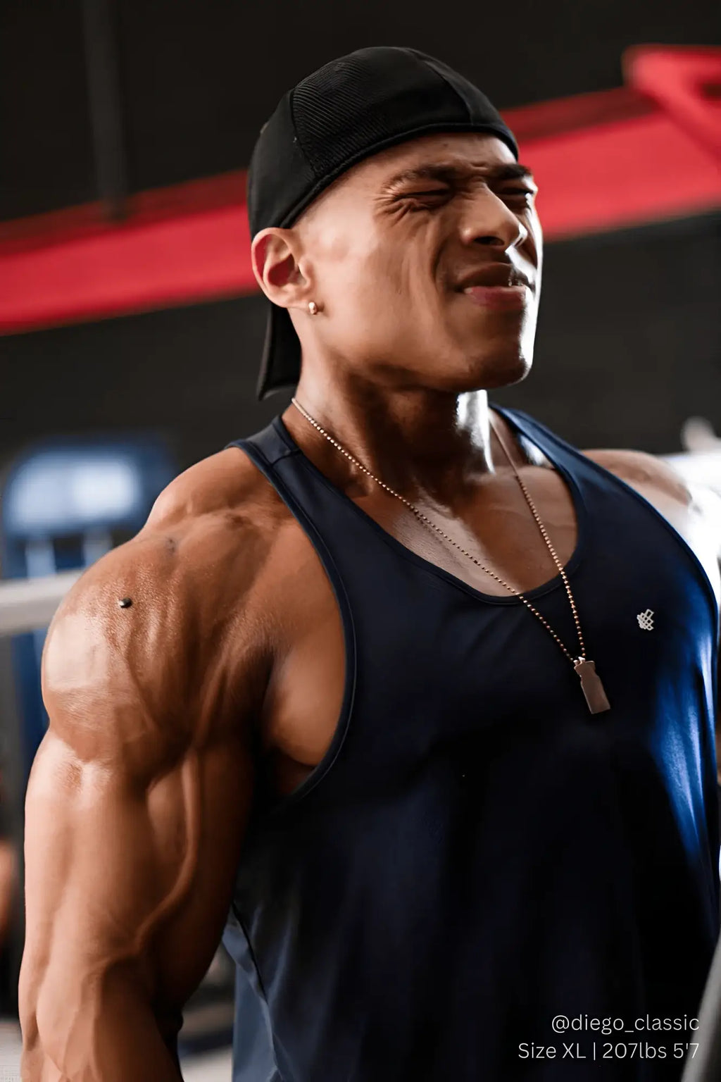 Muscular man wearing a black cap with navy jed north fast-dry bodybuilding workout stringer visible from the back