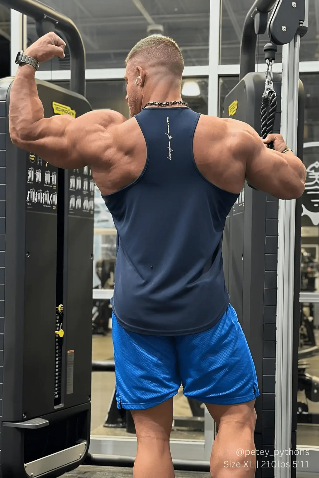 Muscular man wearing a navy Jed North fast-dry bodybuilding workout stringer exercising at the gym