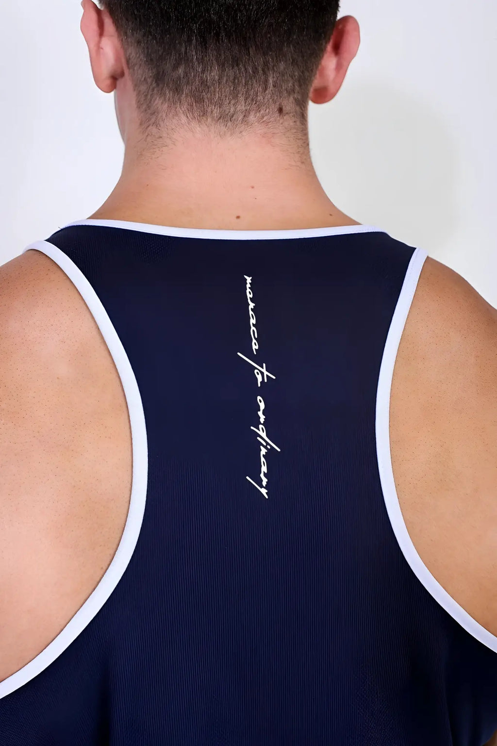 Back view of navy blue fast-dry bodybuilding workout stringer tank top with white trim and marseille for everybody logo