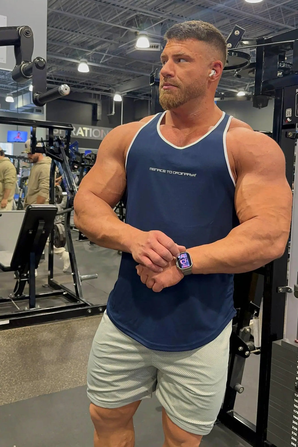 Man wearing a silver apple watch with rectangular face and minimalist design and a navy fast-dry bodybuilding workout stringer