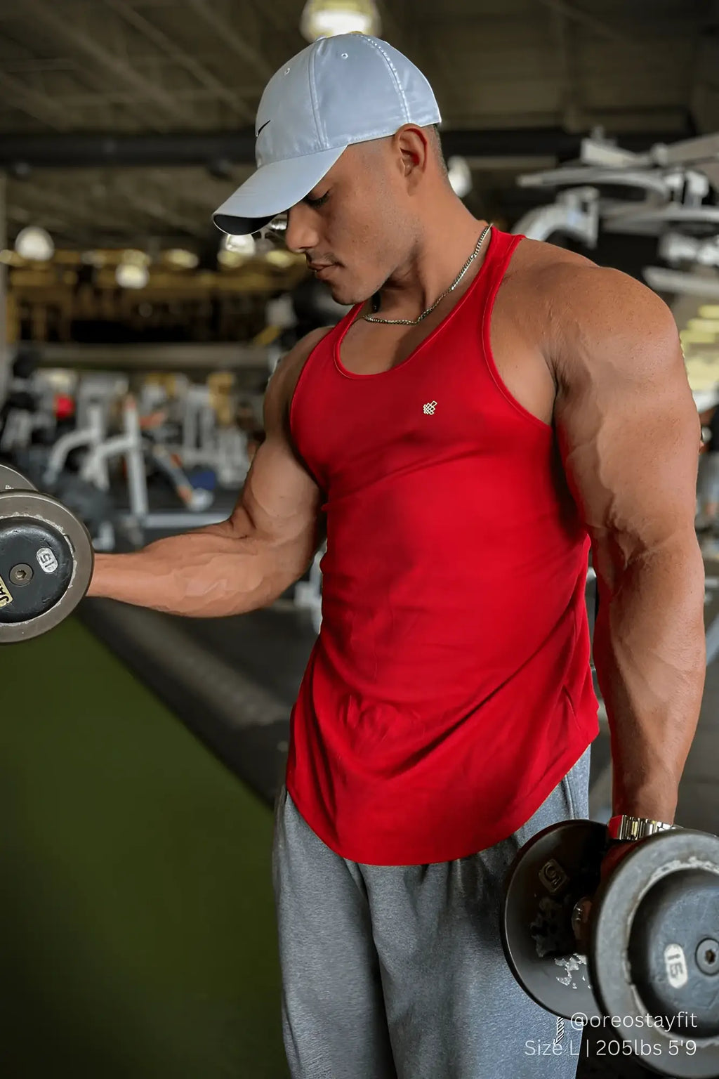 Man wearing a red fast-dry bodybuilding workout stringer tank top with a small chest logo in a gym setting