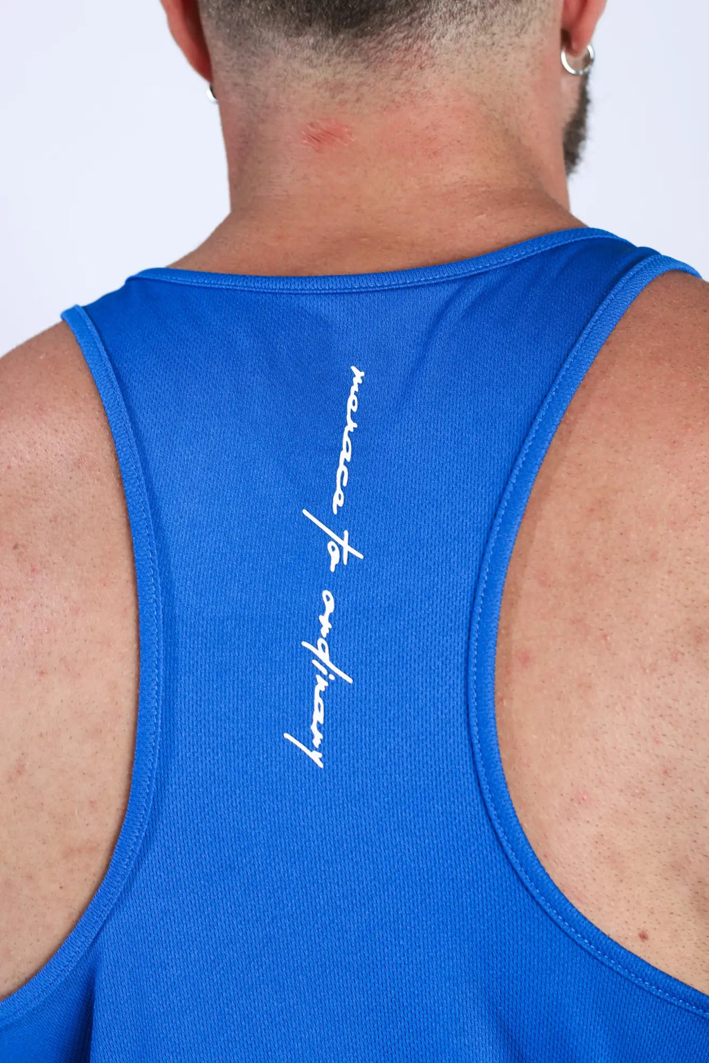 Back view of royal blue fast-dry bodybuilding workout stringer tank top with white cursive text on the back