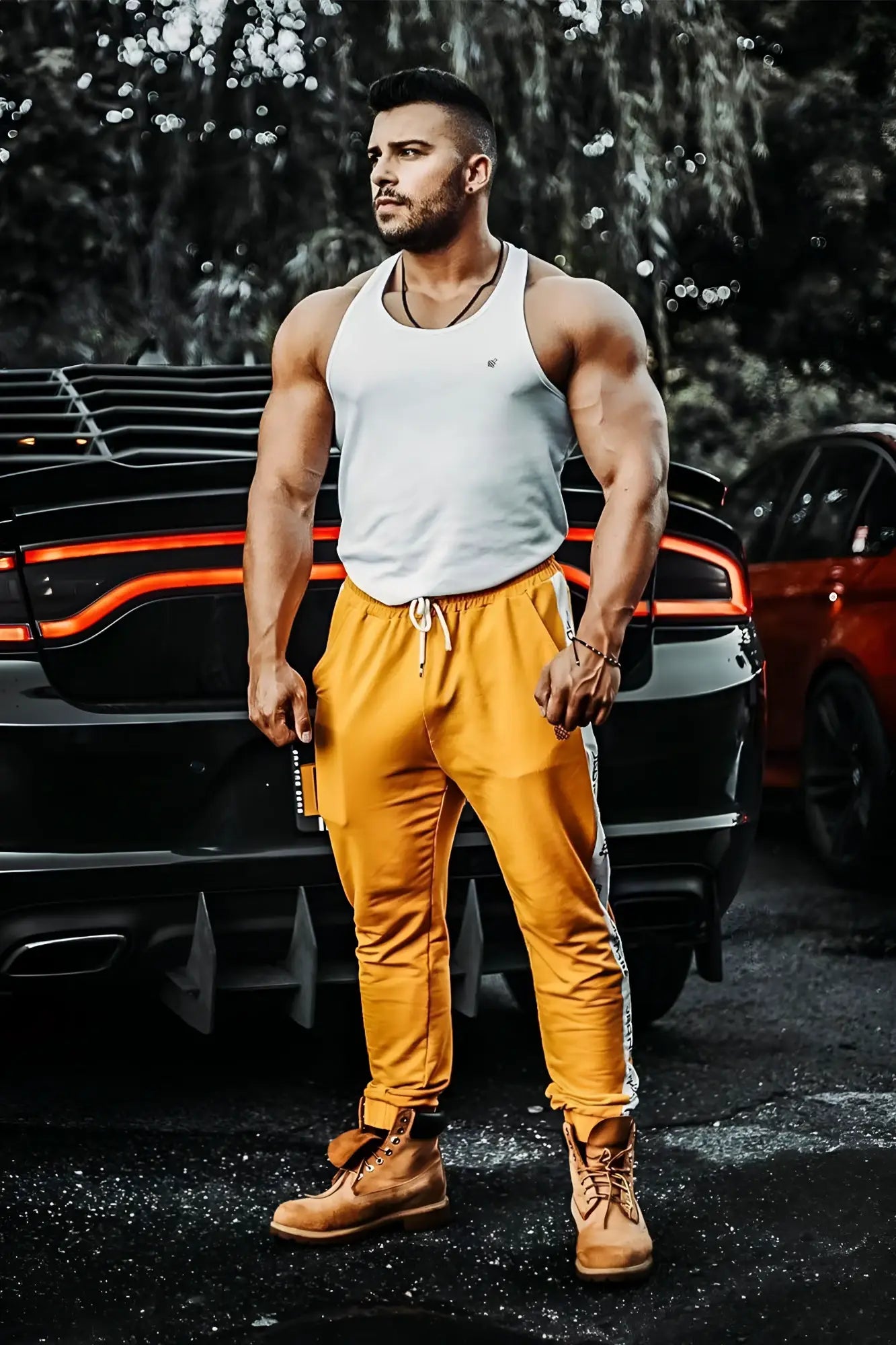 A muscular man wears a white jed north fast-dry bodybuilding workout stringer tank top standing by a black car