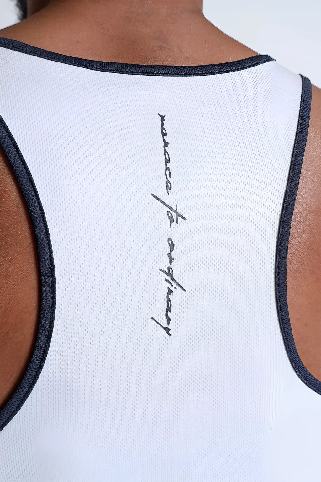 Back view of white fast-dry bodybuilding workout stringer with navy trim and cursive maecca to ordinary logo