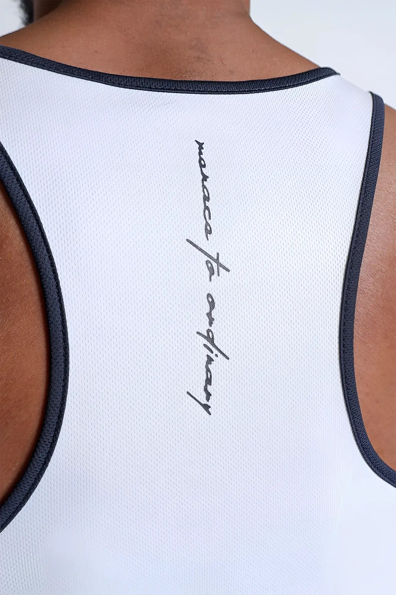 Back view of white fast-dry bodybuilding workout stringer with navy trim and cursive maecca to ordinary logo