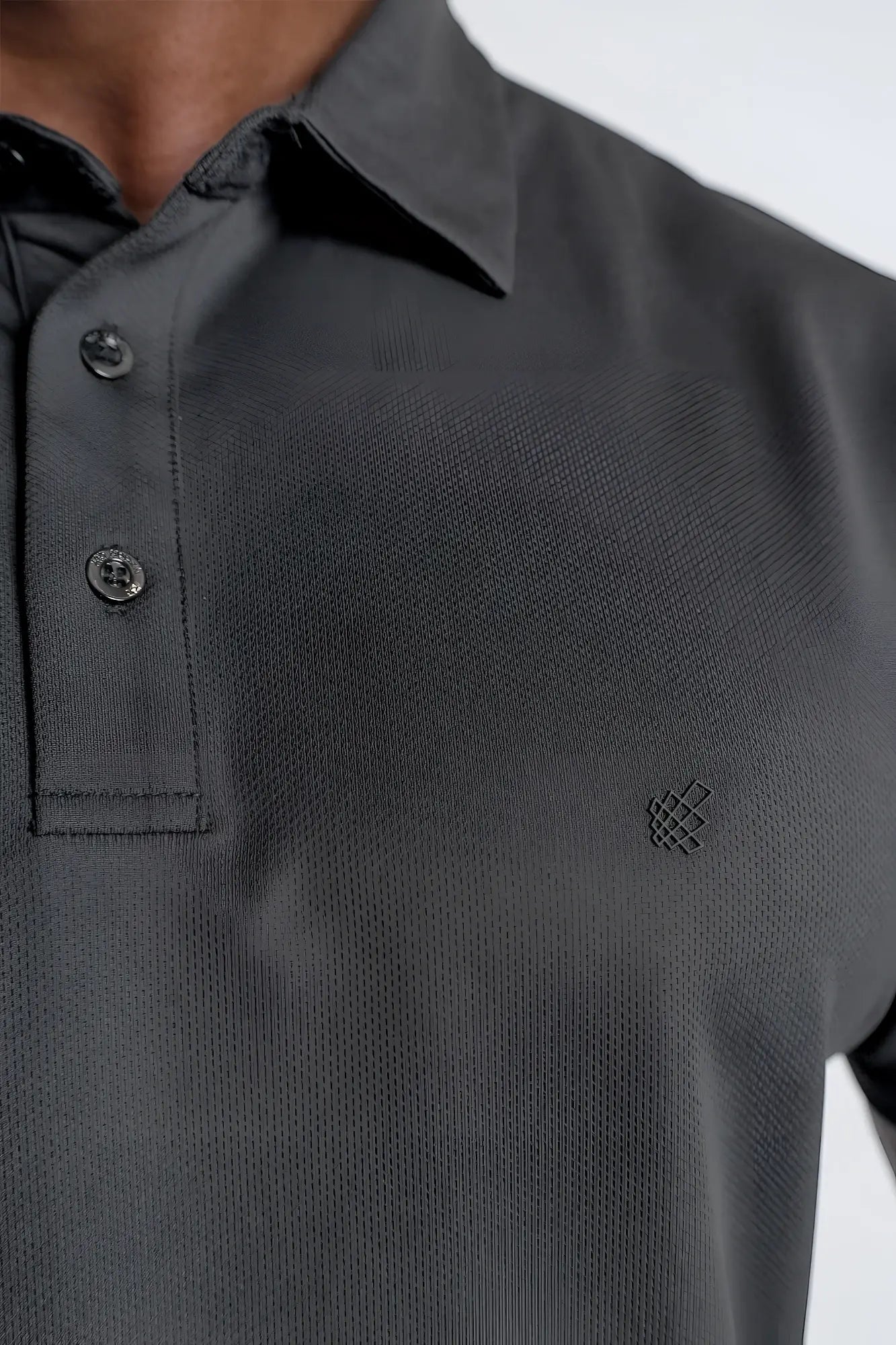 Dark gray fast dry polo t shirt with dark textured fabric and subtle black embroidered logo on the chest