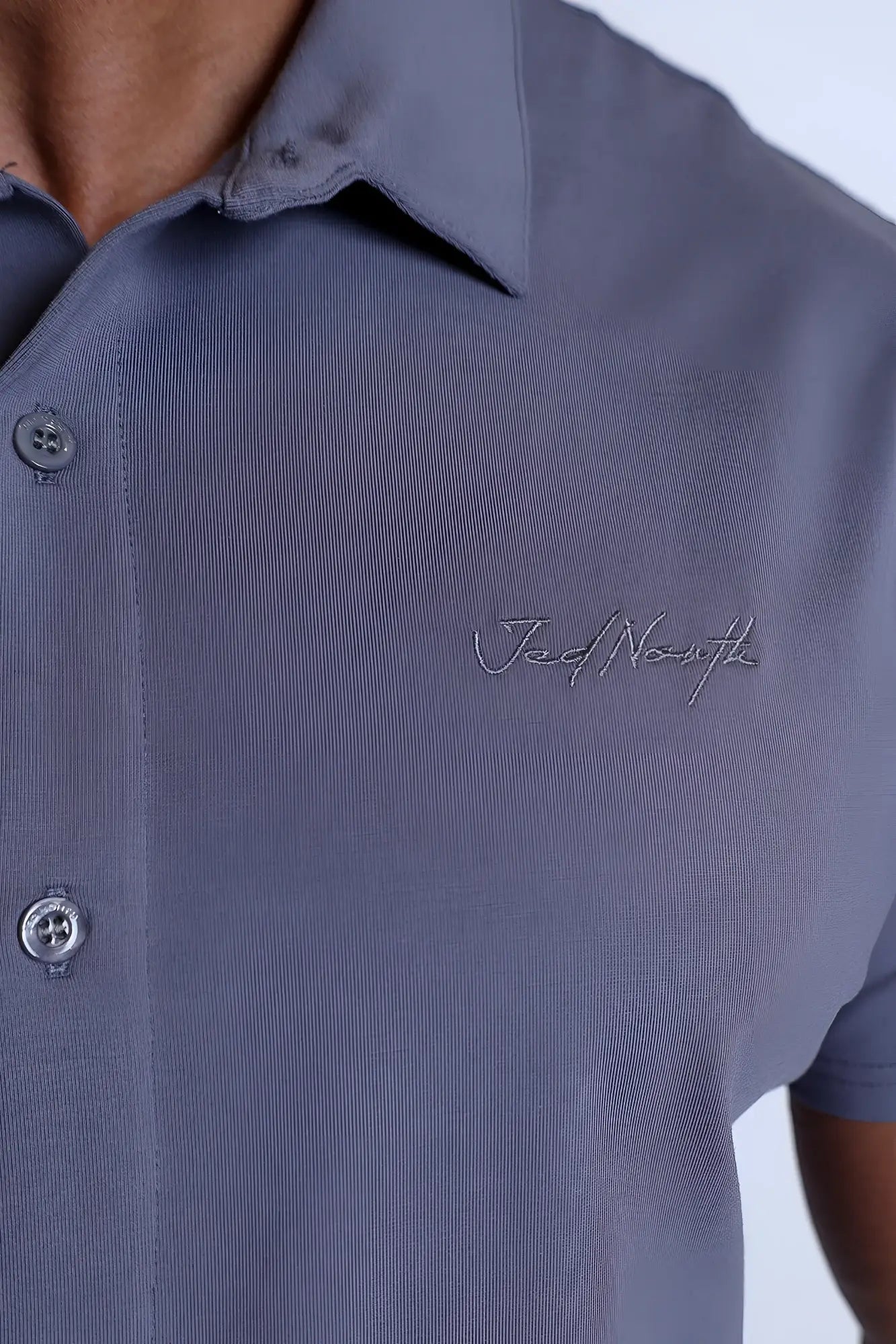 Navy blue short-sleeved polo shirt with ribbed texture and subtle embroidered logo on the chest in storm gray flex premium stretch fabric