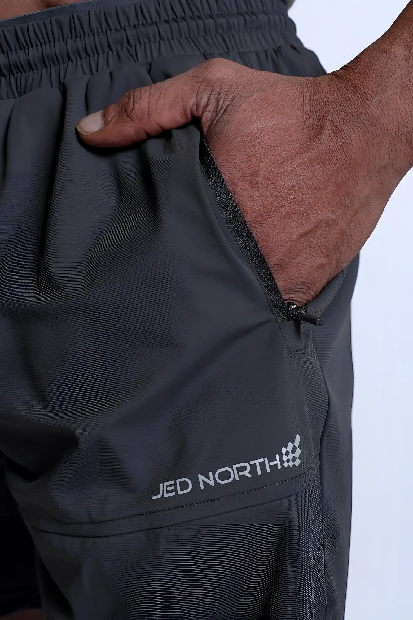 Fortis men’s athletic shorts in black with subtle textured fabric and white jed north logo on the lower leg