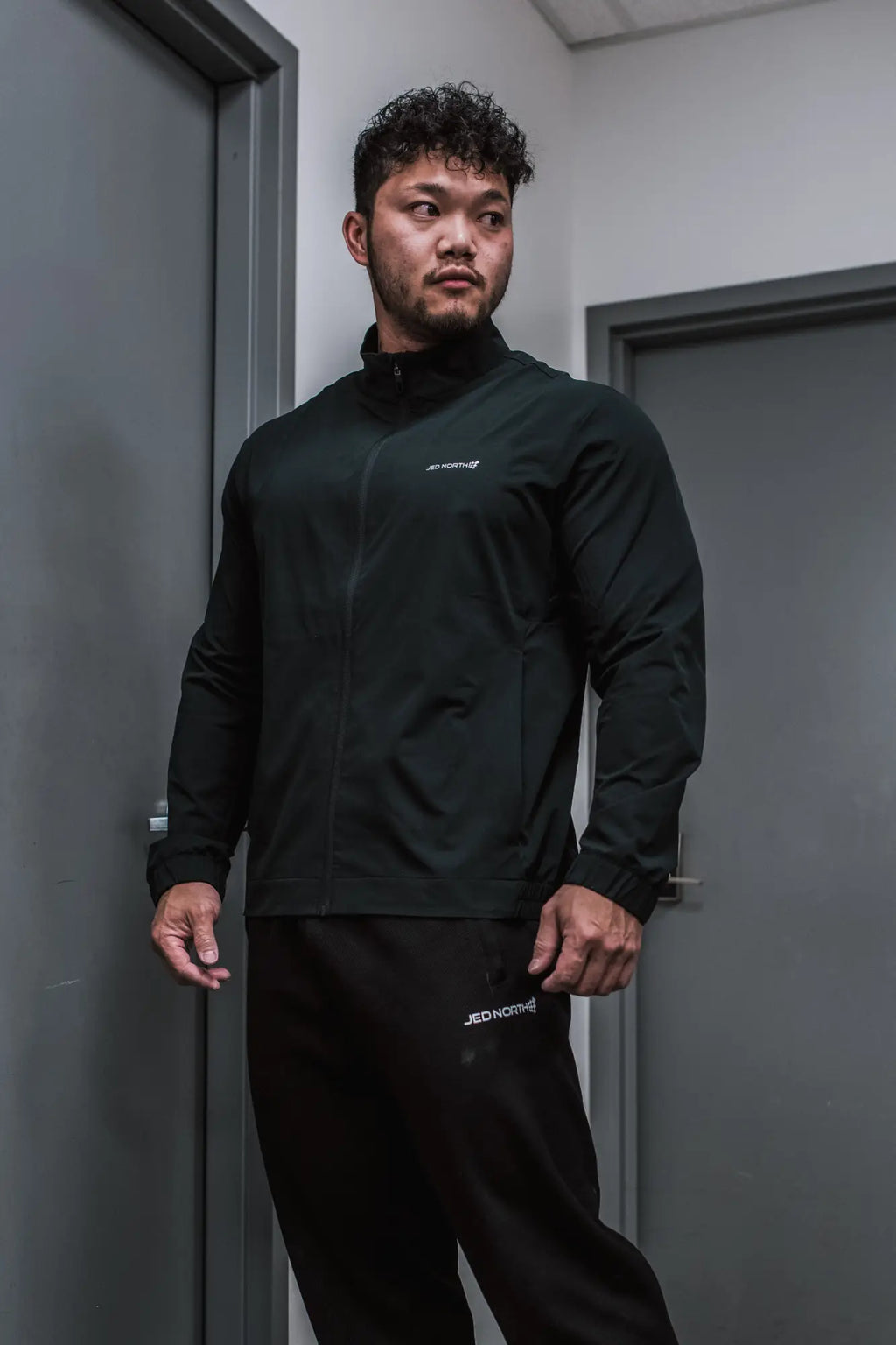Black full-zip training jacket with subtle white branding on chest and sleeve perfect for athletic use