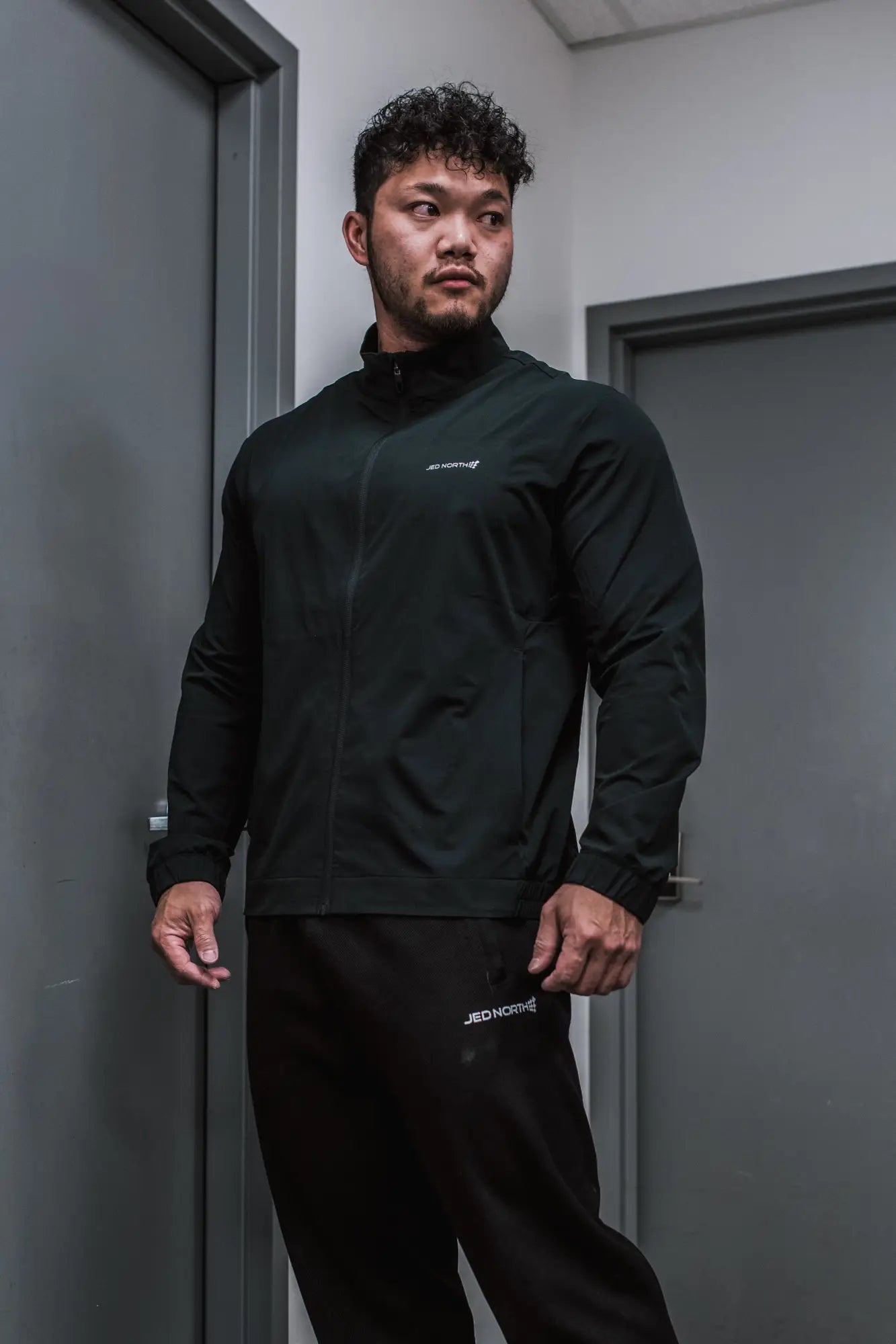 Black full-zip training jacket with subtle white branding on chest and sleeve perfect for athletic use