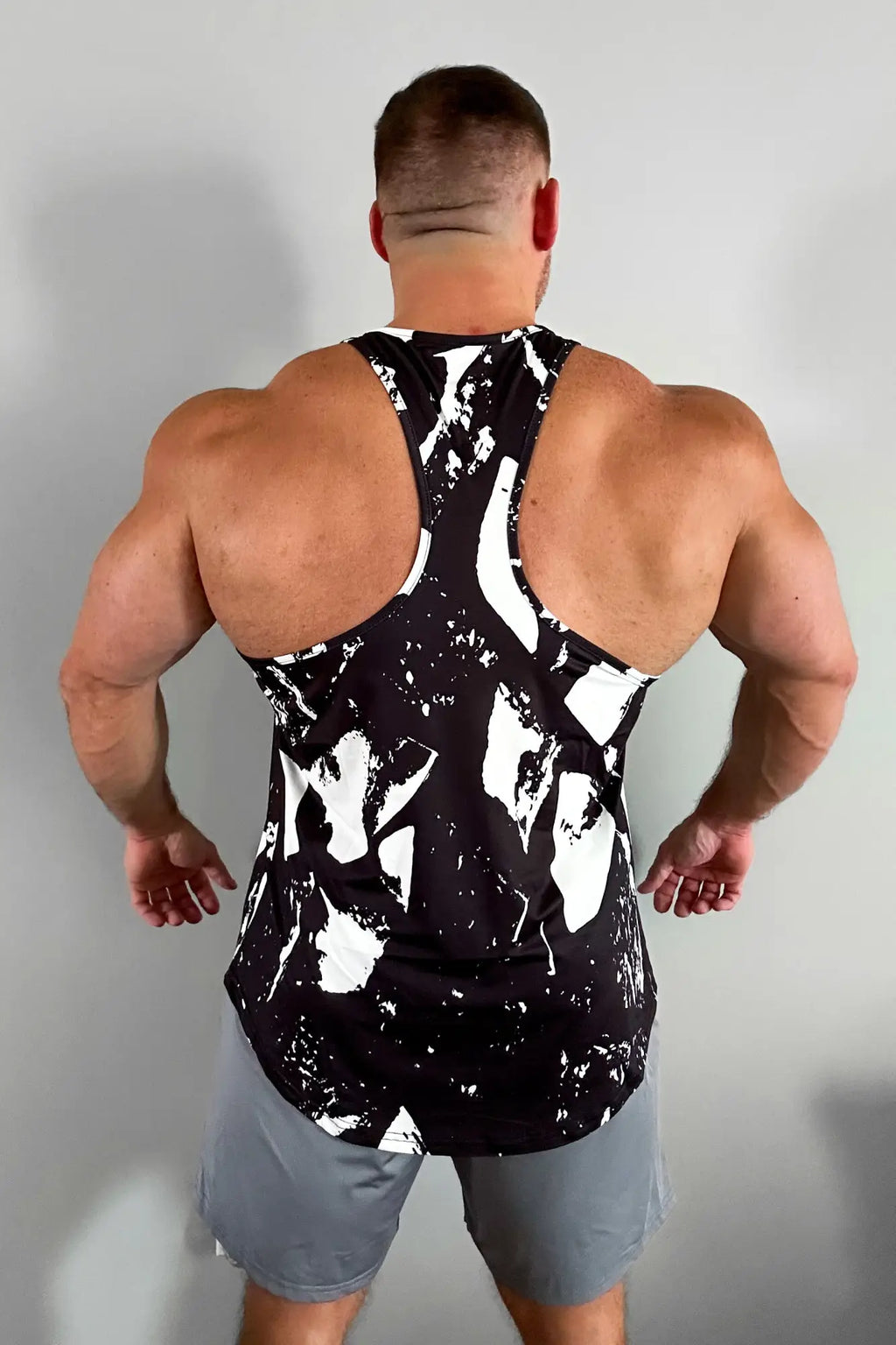 Black and white abstract splatter patterned graphic muscle stringer tank top with breathable fabric for athletic use