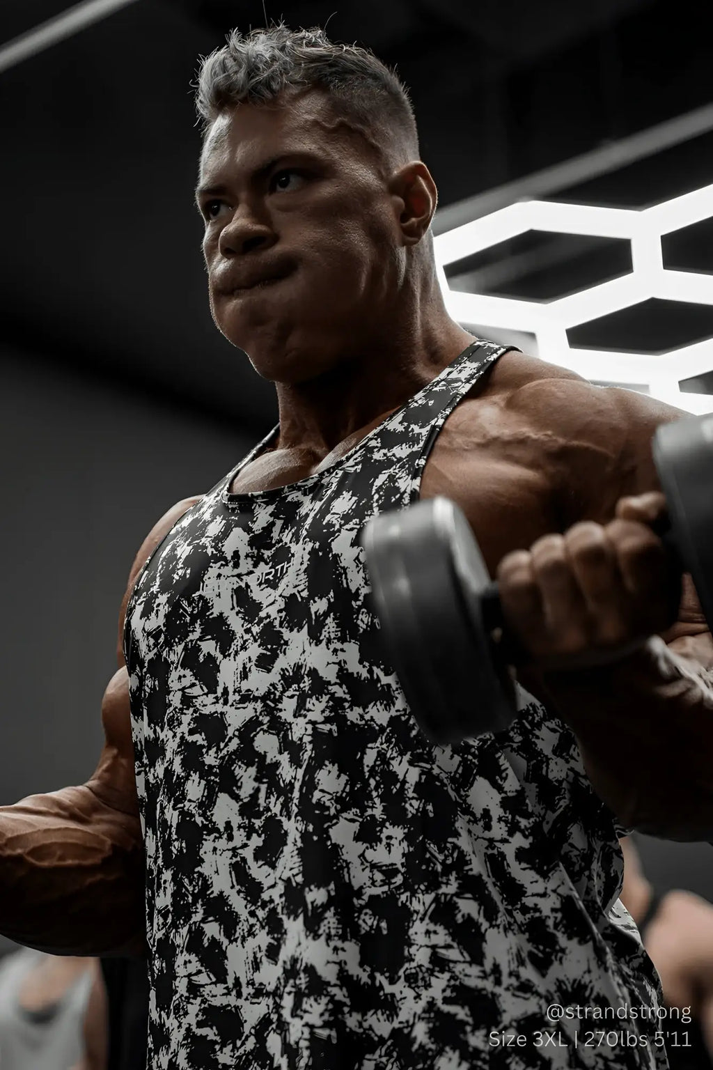 A muscular man wearing a jed north graphic muscle stringer tank top with black and white paint brush abstract pattern