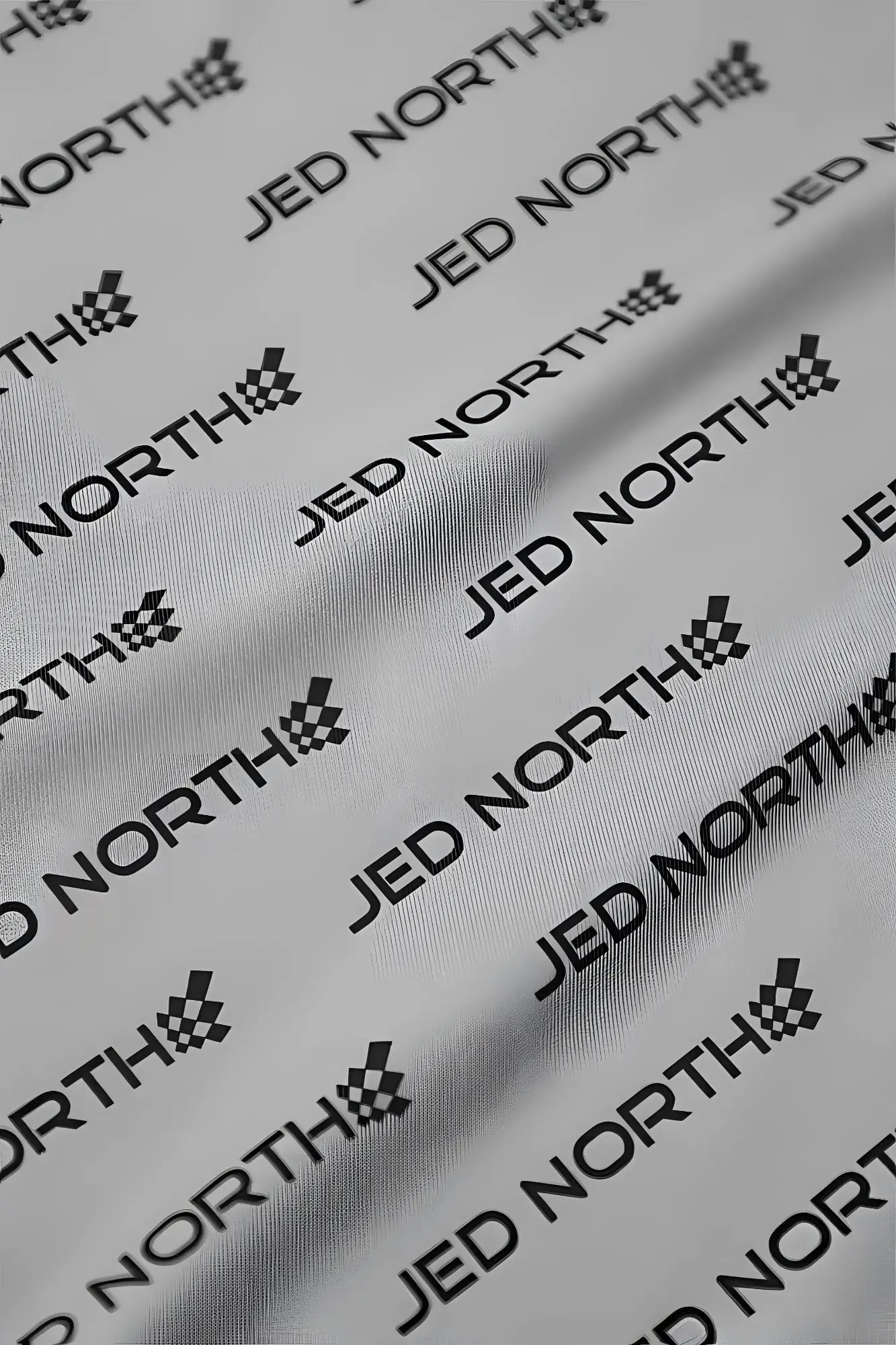 White fabric featuring repeating black jed north logo and checkered flag emblem from jed north graphic muscle stringer gray jn logo