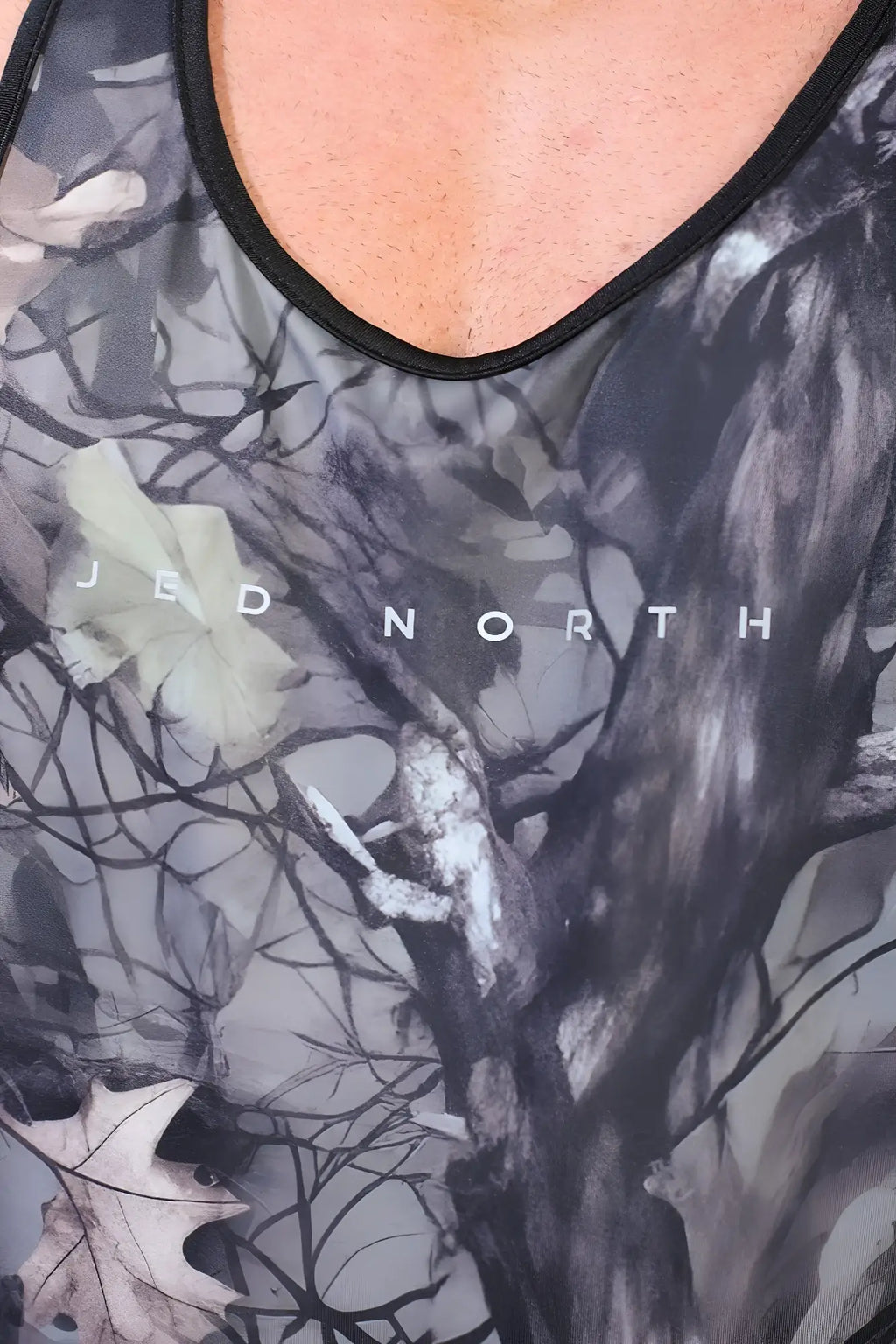 A black and gray camouflage muscle stringer tank top with subtle leaf design and jed north text on the chest