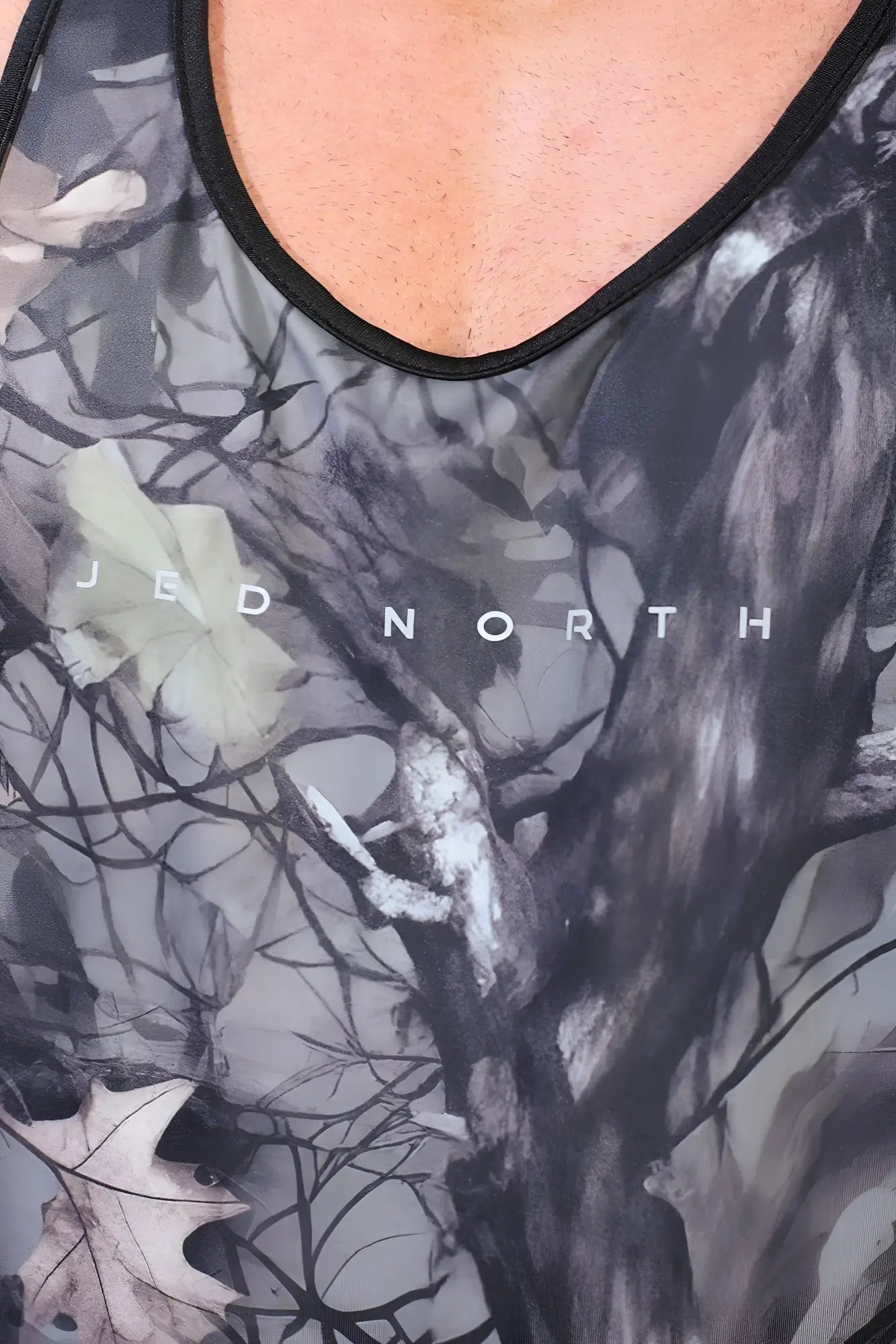 A black and gray camouflage muscle stringer tank top with subtle leaf design and jed north text on the chest