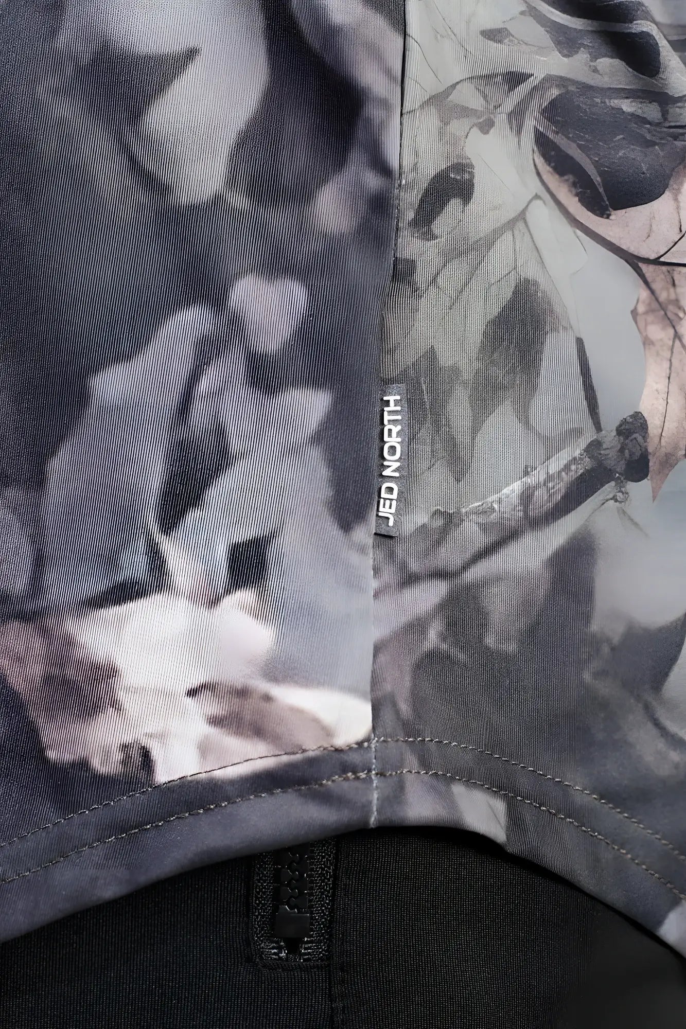 Gray and black leaf-patterned fabric of jed north graphic muscle stringer with hunter camo brand tag visible