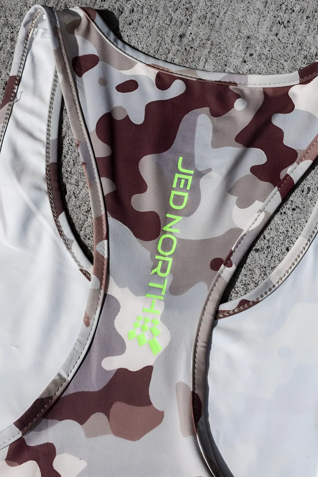 A khaki camo racerback tank top with neon green jed north branding called Jed North Graphic Muscle Stringer