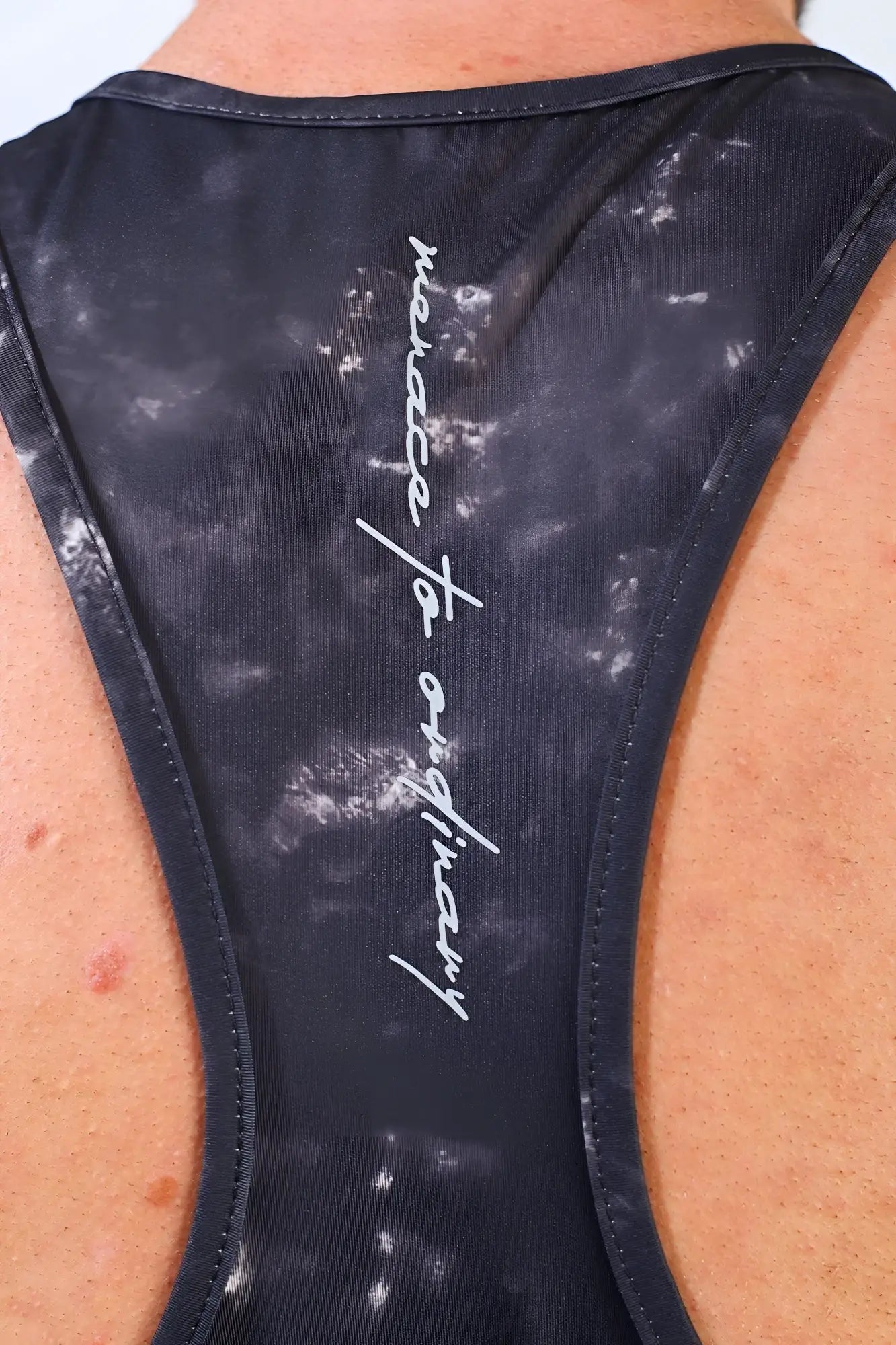 Back side of black tie-dye jed north graphic muscle stringer racerback tank top with white malice to ordinary text